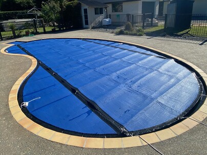 Kidney shaped swimming pool cover with flaps